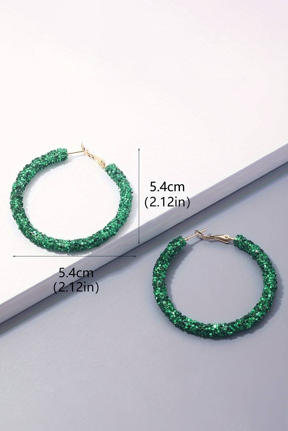 Green hoop earrings with measurements on a light gray background