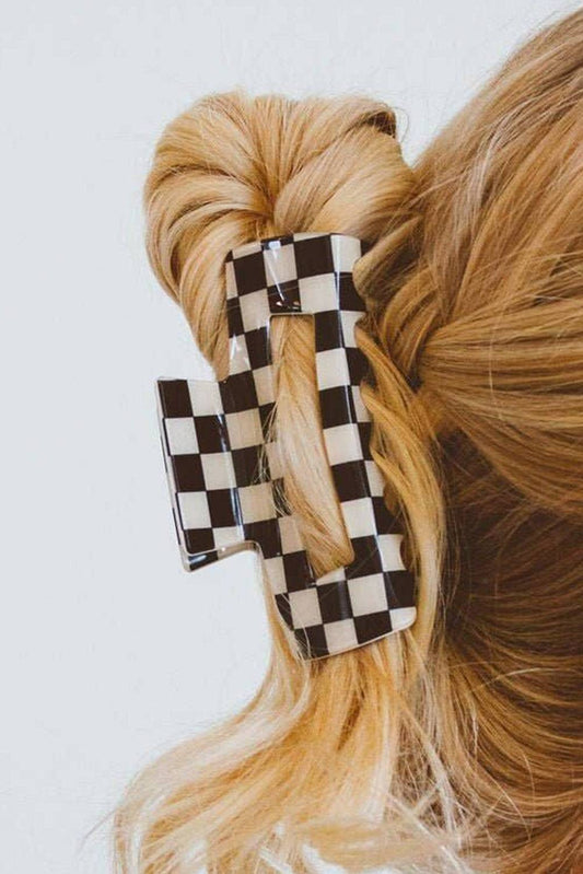 Black and white checkered hair clip in blonde hair on a white background