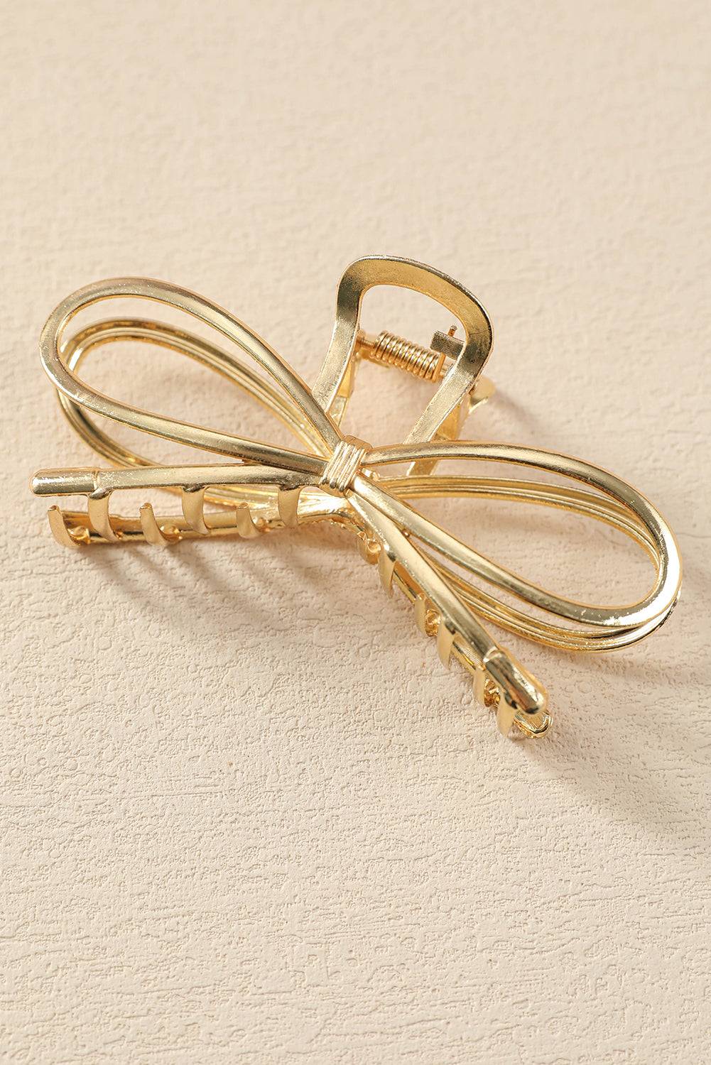 Gold bow-shaped hair clip on a beige background