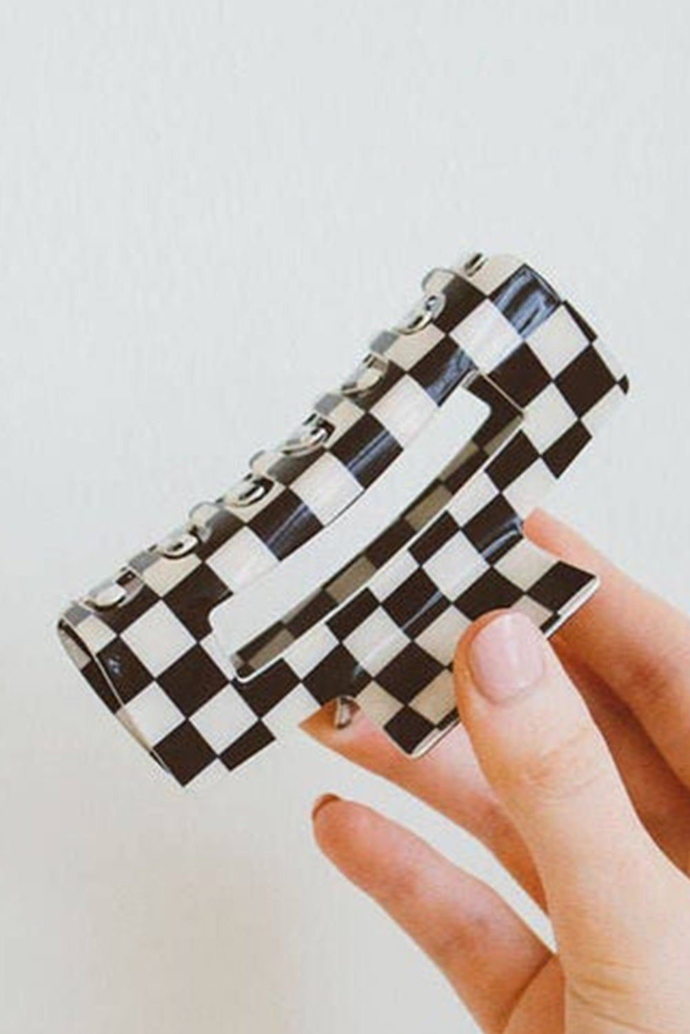 Black and white checkered wallet held by a hand against a light background