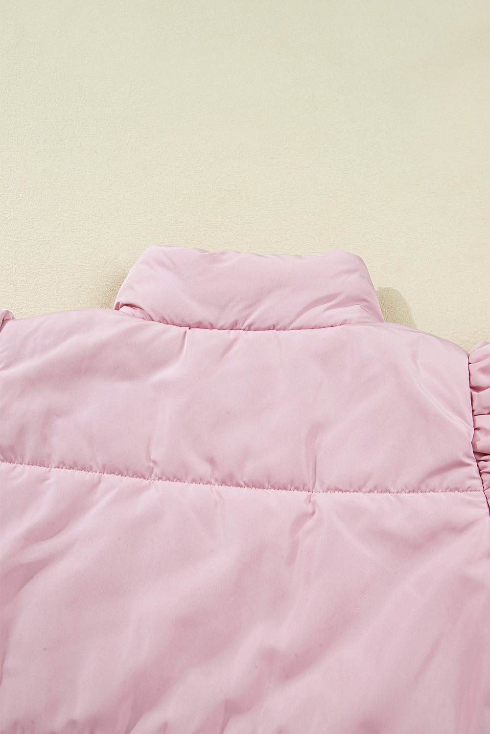 Close-up of a pink puffer vest on a light beige background