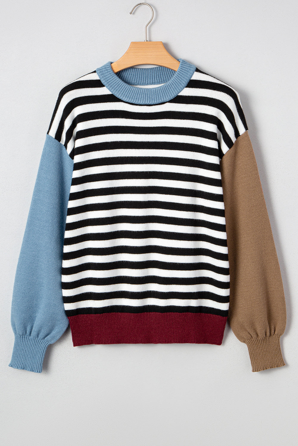 Striped sweater with blue and brown sleeves on a hanger against a white background