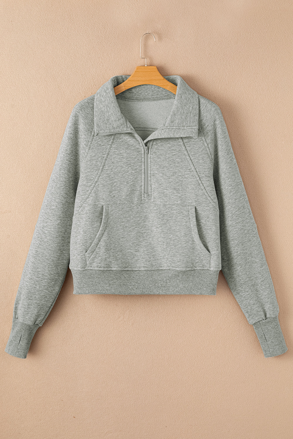 Gray sweatshirt on a hanger against a beige background