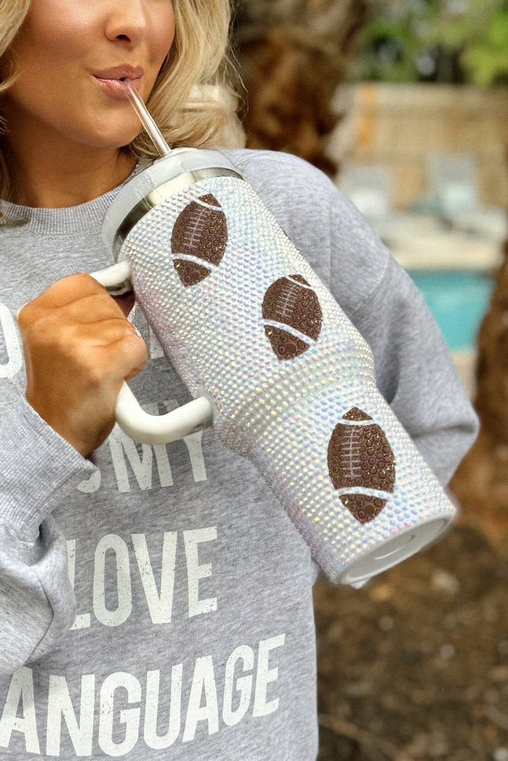Person holding a tumbler with football designs outdoors