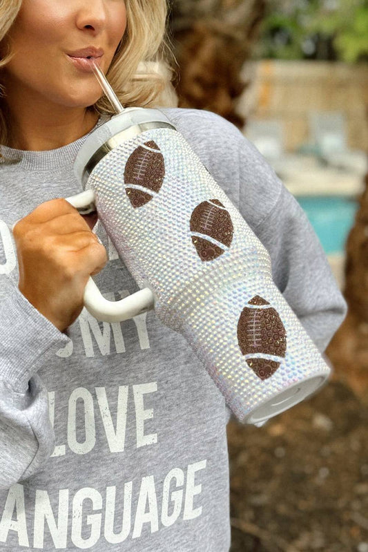 Person holding a tumbler with football designs outdoors