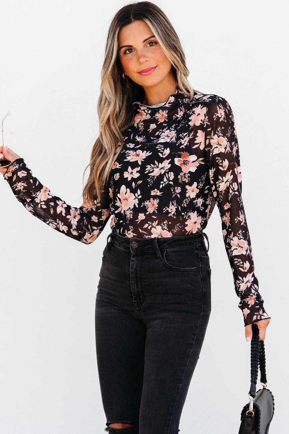 Woman wearing a floral long-sleeve top and black jeans  