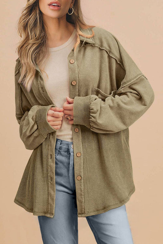Woman wearing a green jacket over a white shirt and blue jeans on a beige background