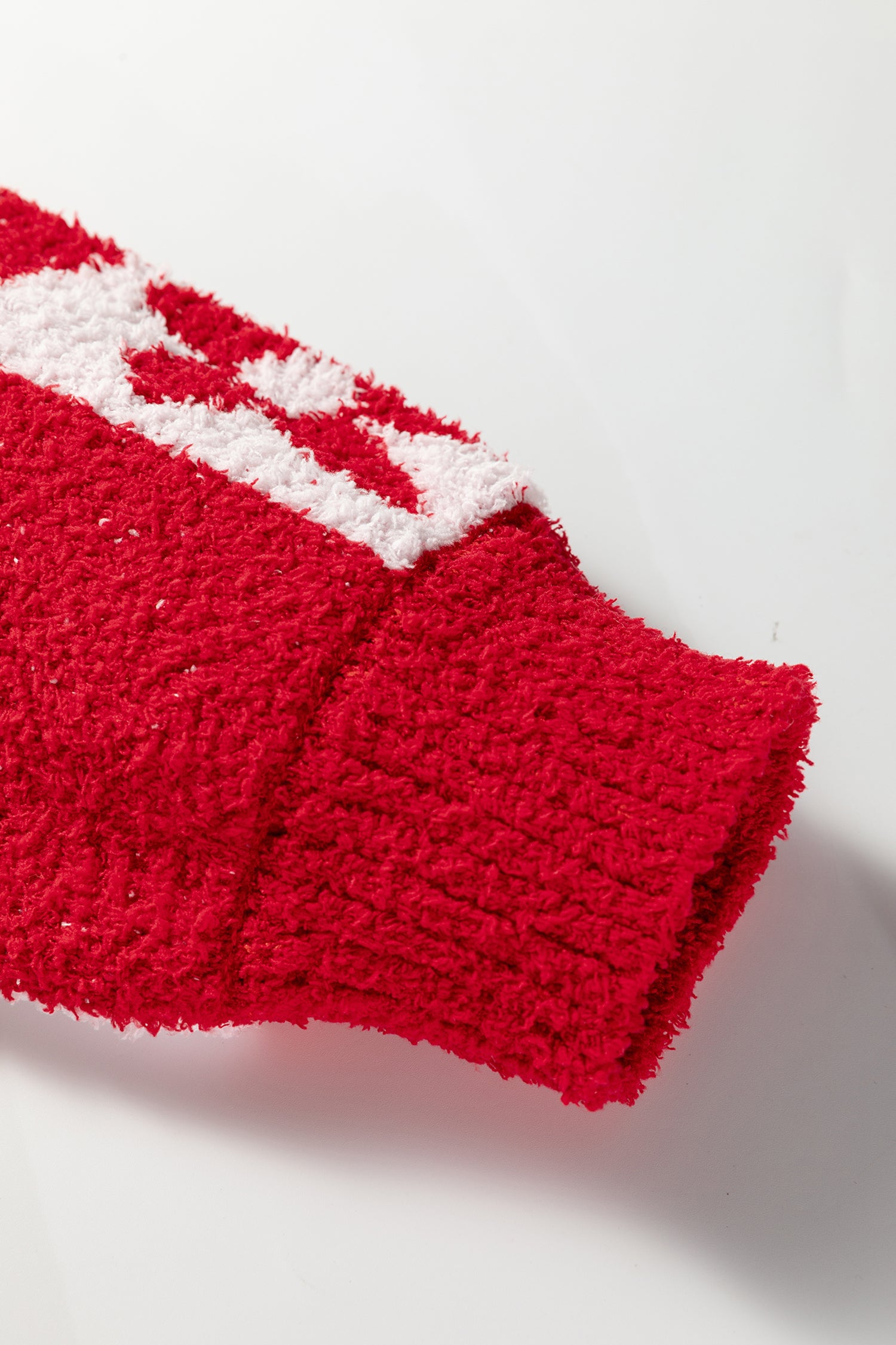 Close-up of a red knitted item with white pattern on a light gray background