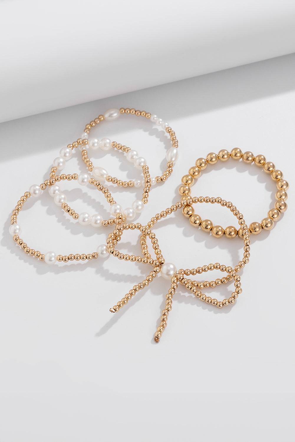 Set of pearl and gold beaded bracelets on a light background