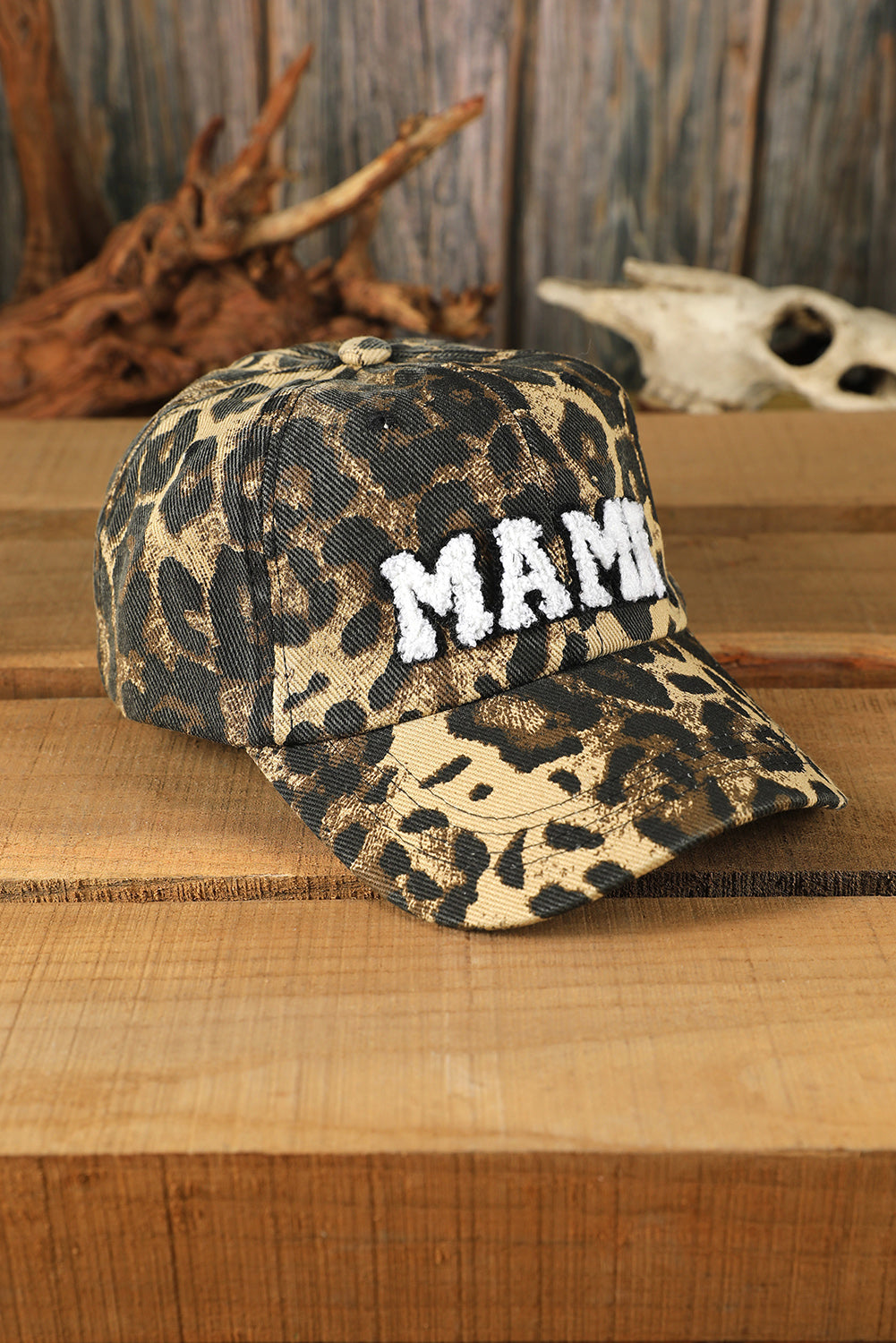 Leopard print cap with 'MAMA' text on a wooden surface