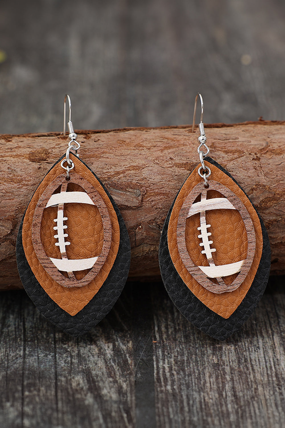 Wooden football-shaped earrings on a wooden surface with a blurred background