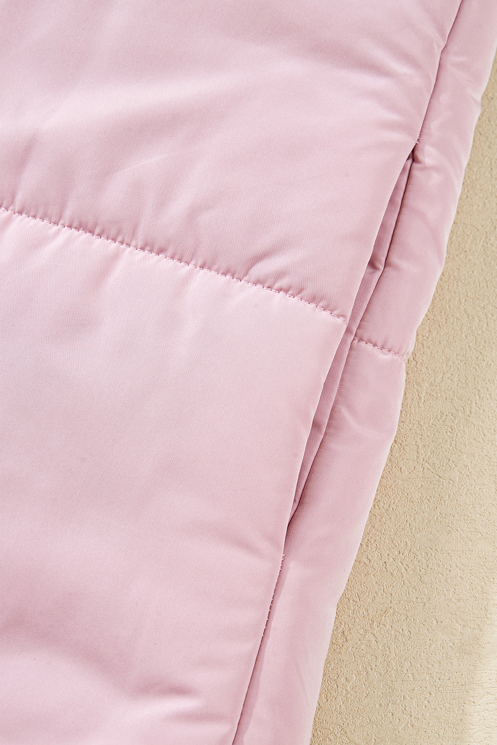 Close-up of a pink quilted jacket on a beige background