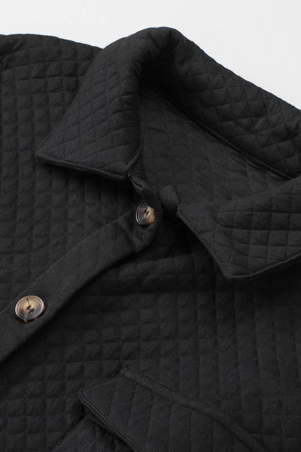 Close-up of a black quilted jacket with button details on a light gray background