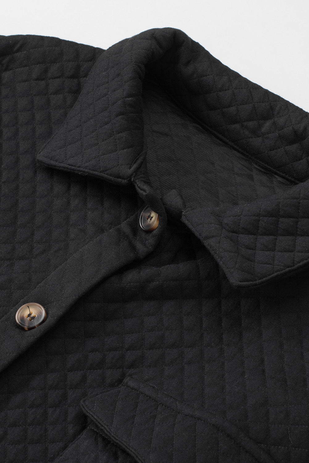 Close-up of a black quilted jacket with button details on a light gray background