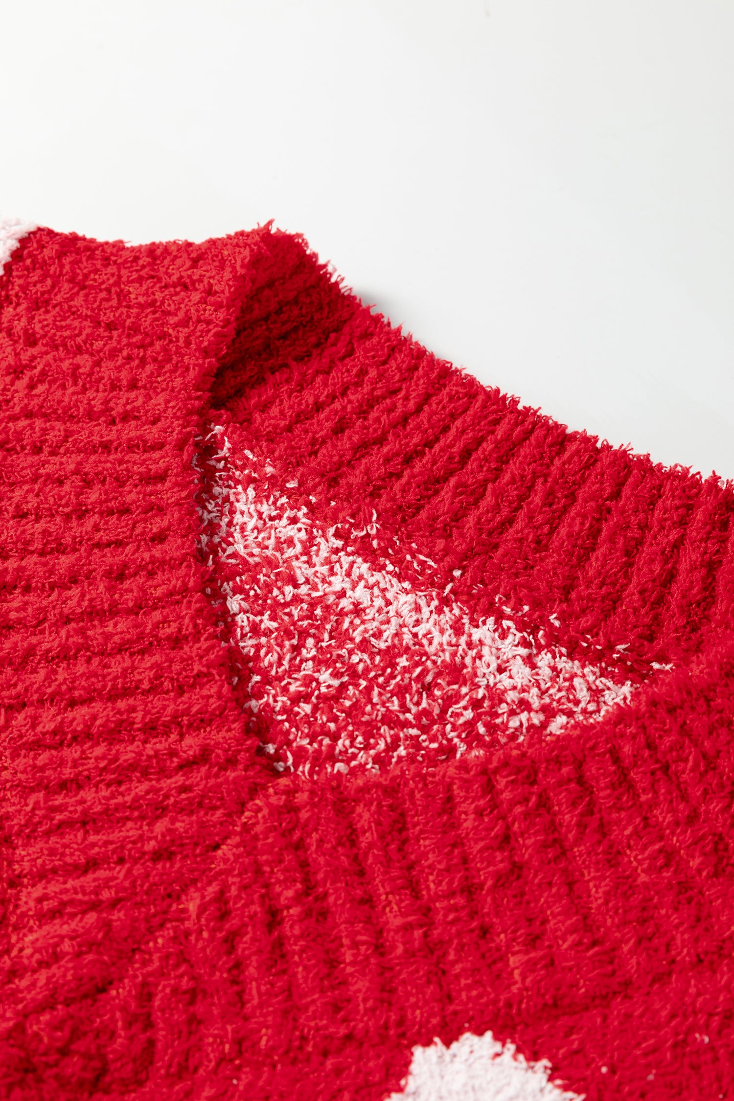 Close-up of a red knitted garment with a white heart design on a white background