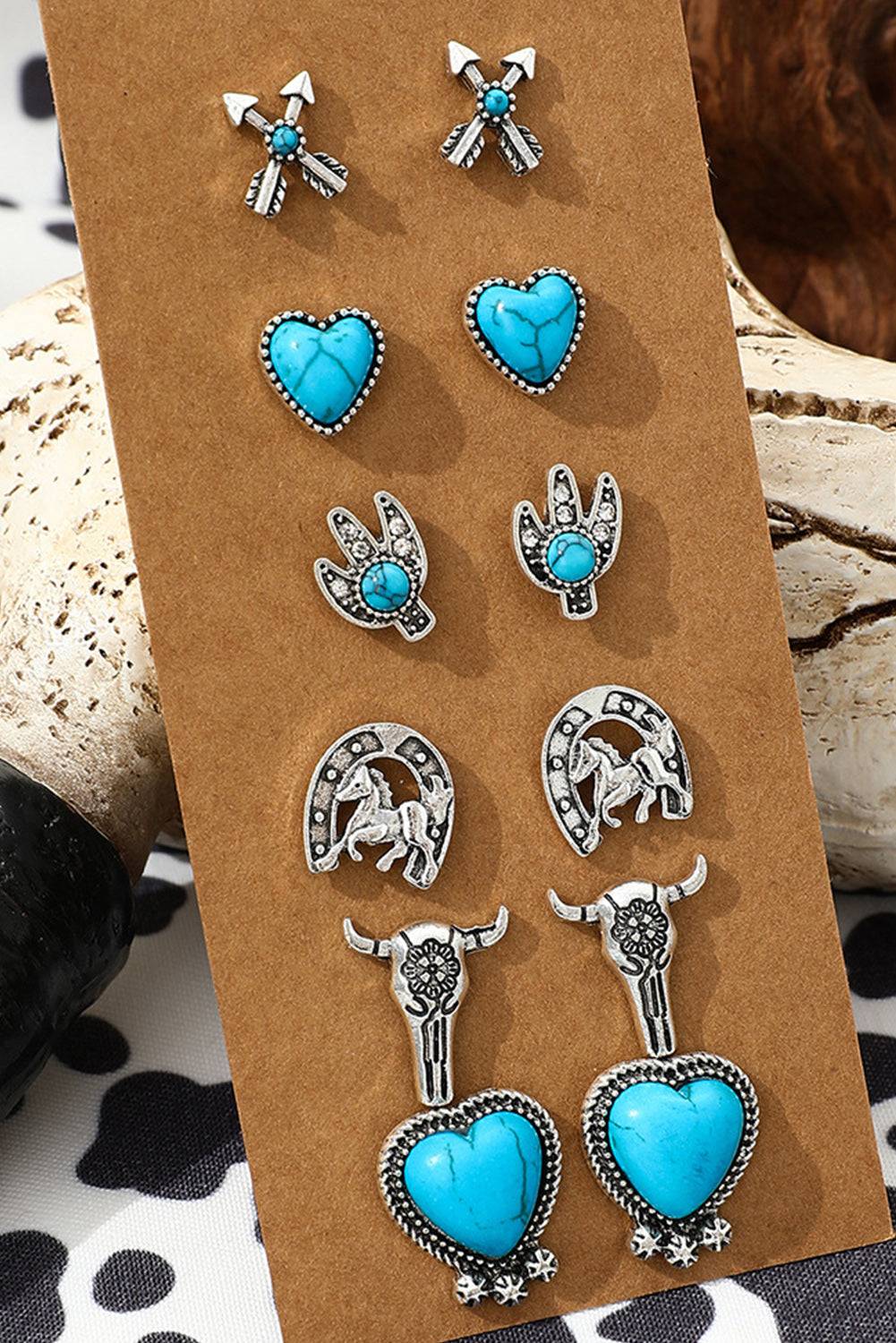 Set of turquoise and silver earrings on a brown card with a rustic background.