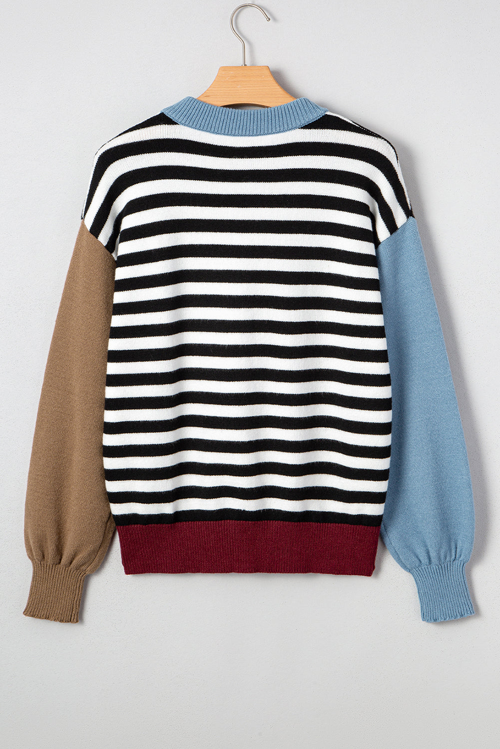 Multicolored striped sweater on a hanger against a light gray background