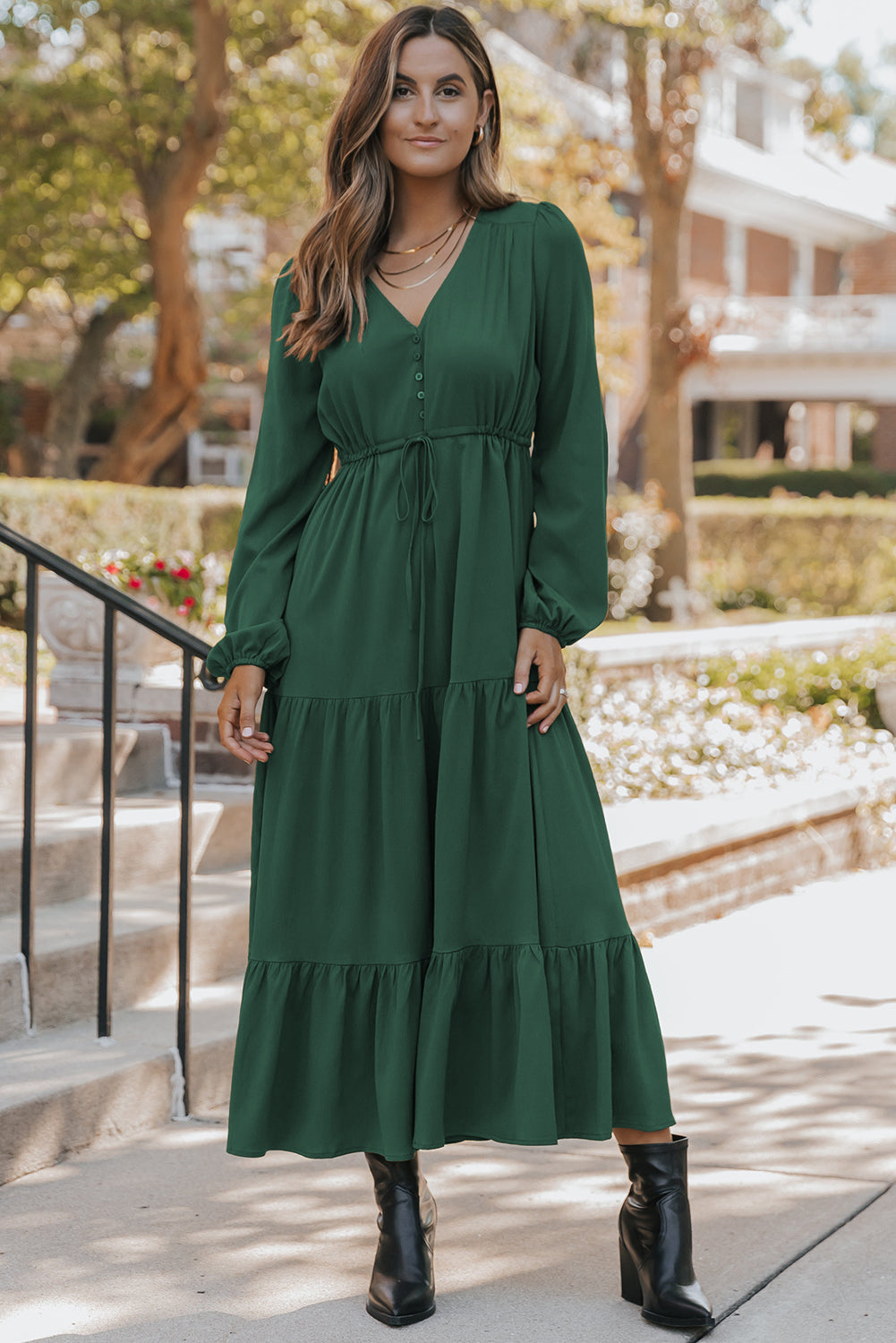 Woman wearing a green dress standing outdoors on a sunny day.