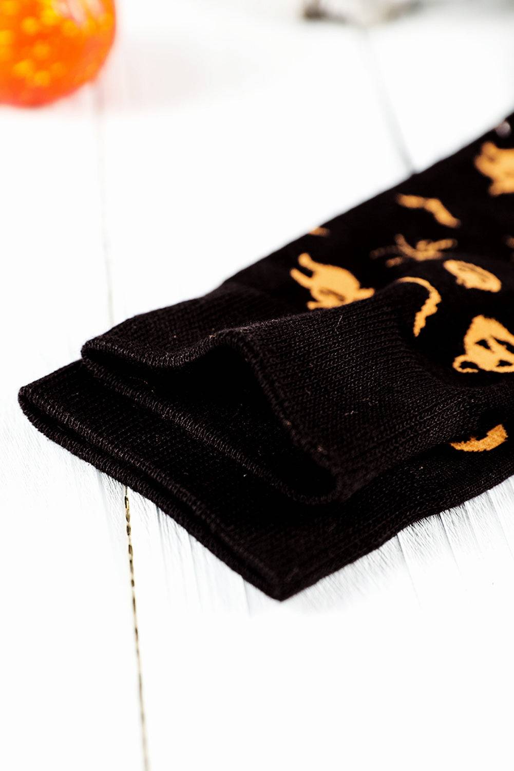 Black socks with gold cat prints on a white surface