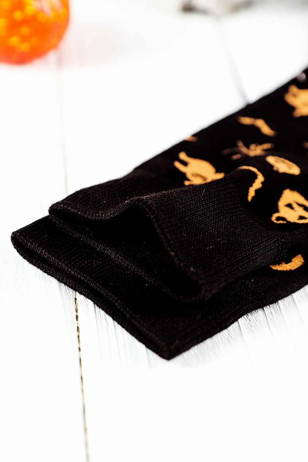 Black socks with gold cat prints on a white surface