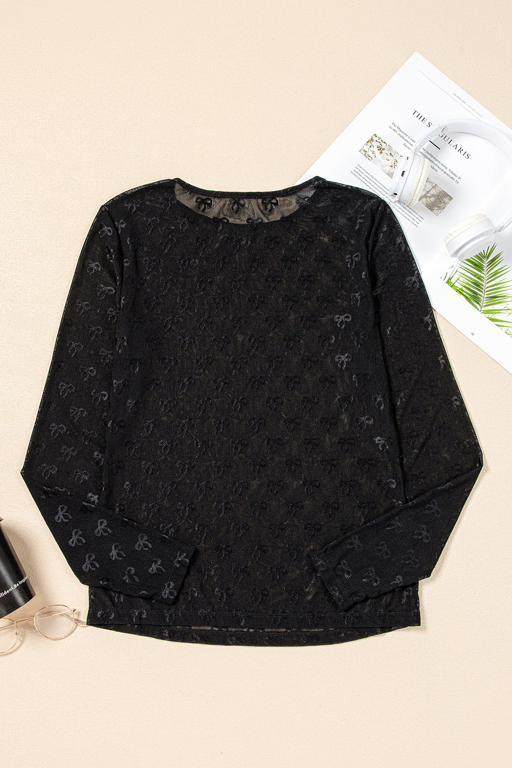 Black patterned sweatshirt on a beige surface with a magazine underneath
