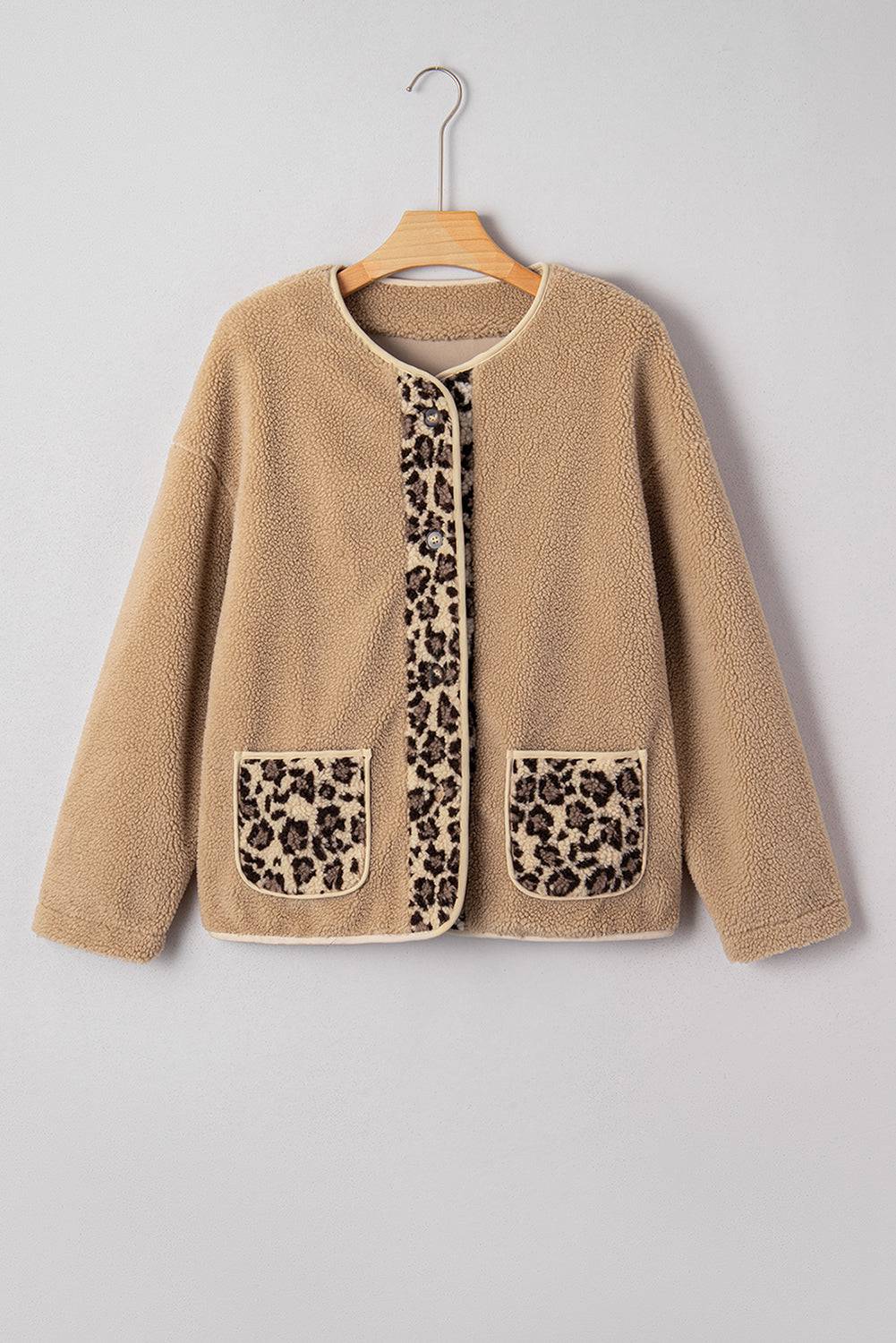 Beige cardigan with leopard print pockets on a hanger against a gray background