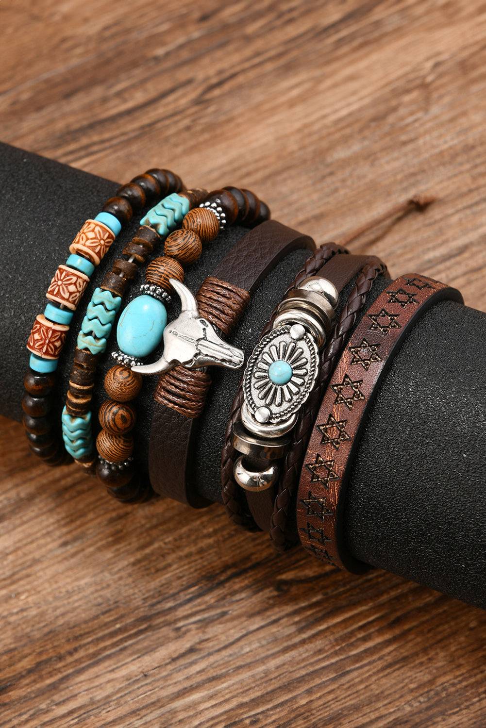 Stack of leather and beaded bracelets on a wrist against a wooden background