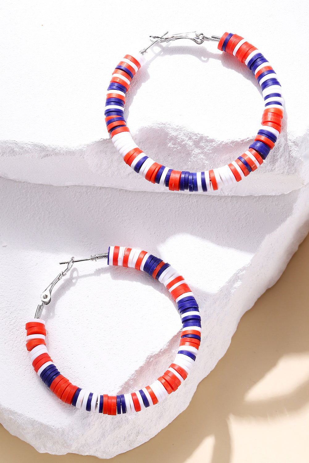 Colorful beaded necklace and earrings on a white stone surface