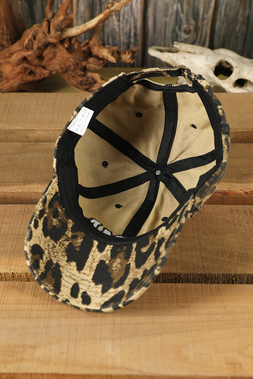 Leopard print cap with black interior on a wooden surface
