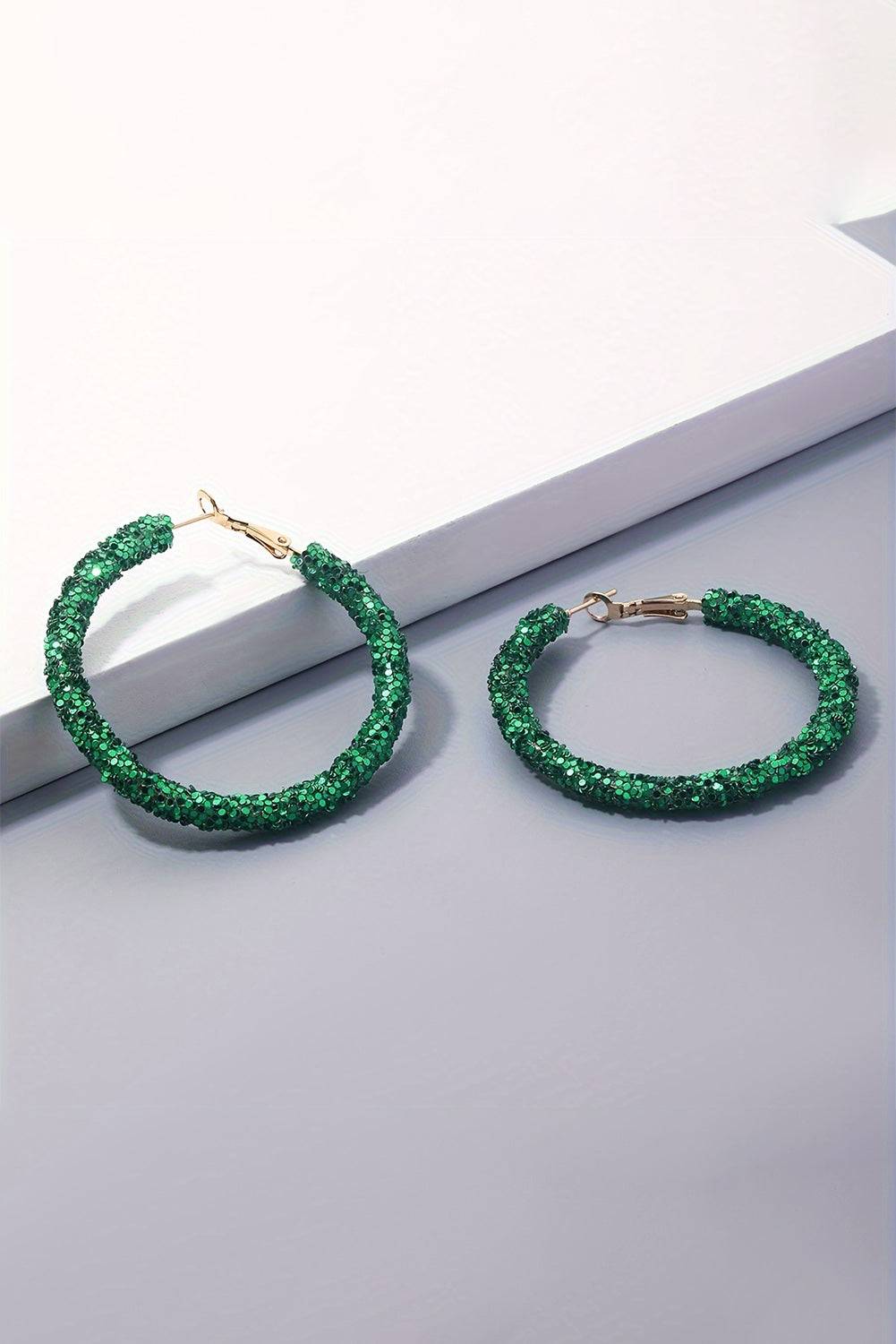 Green hoop earrings on a light gray surface