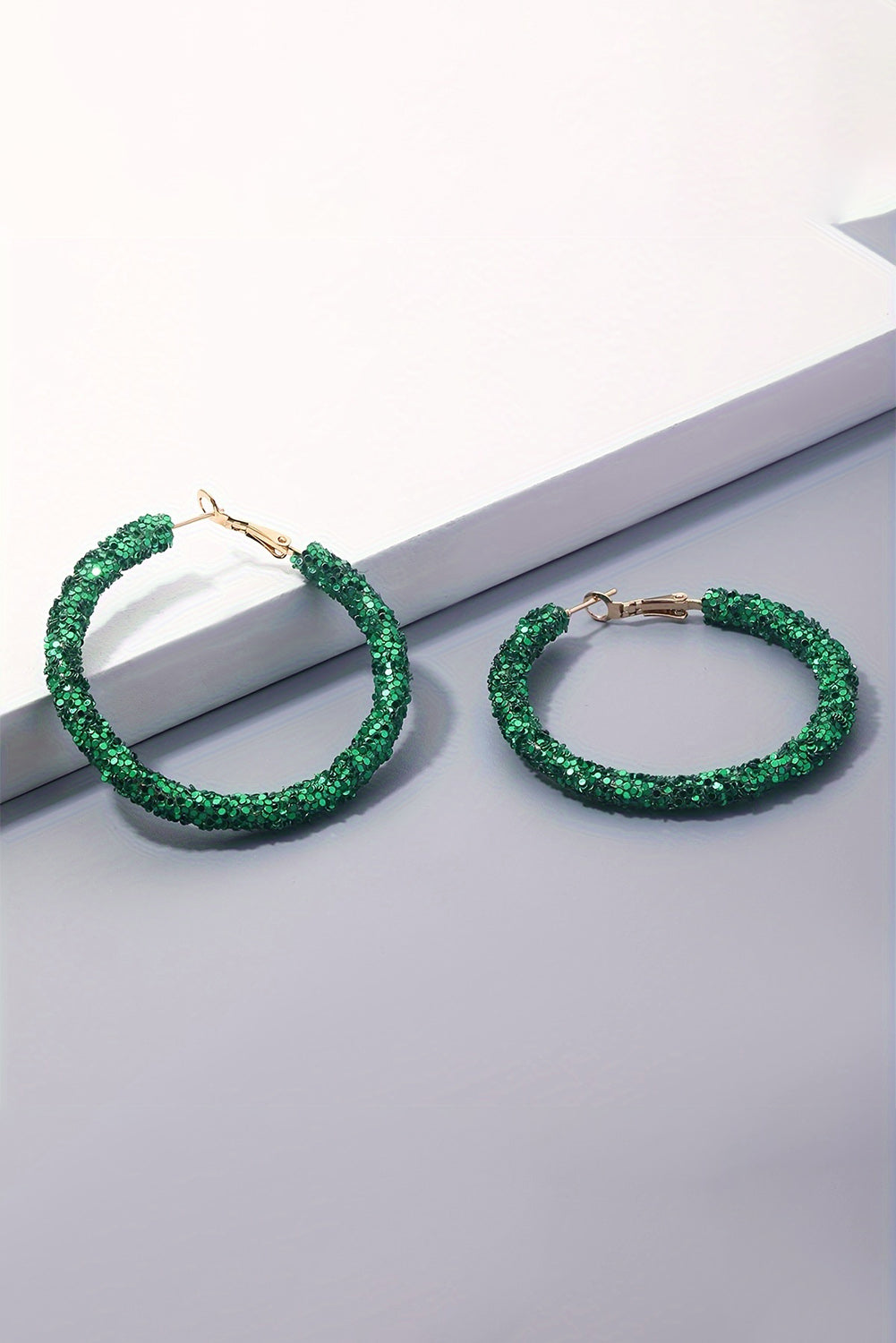 Green hoop earrings on a light gray surface