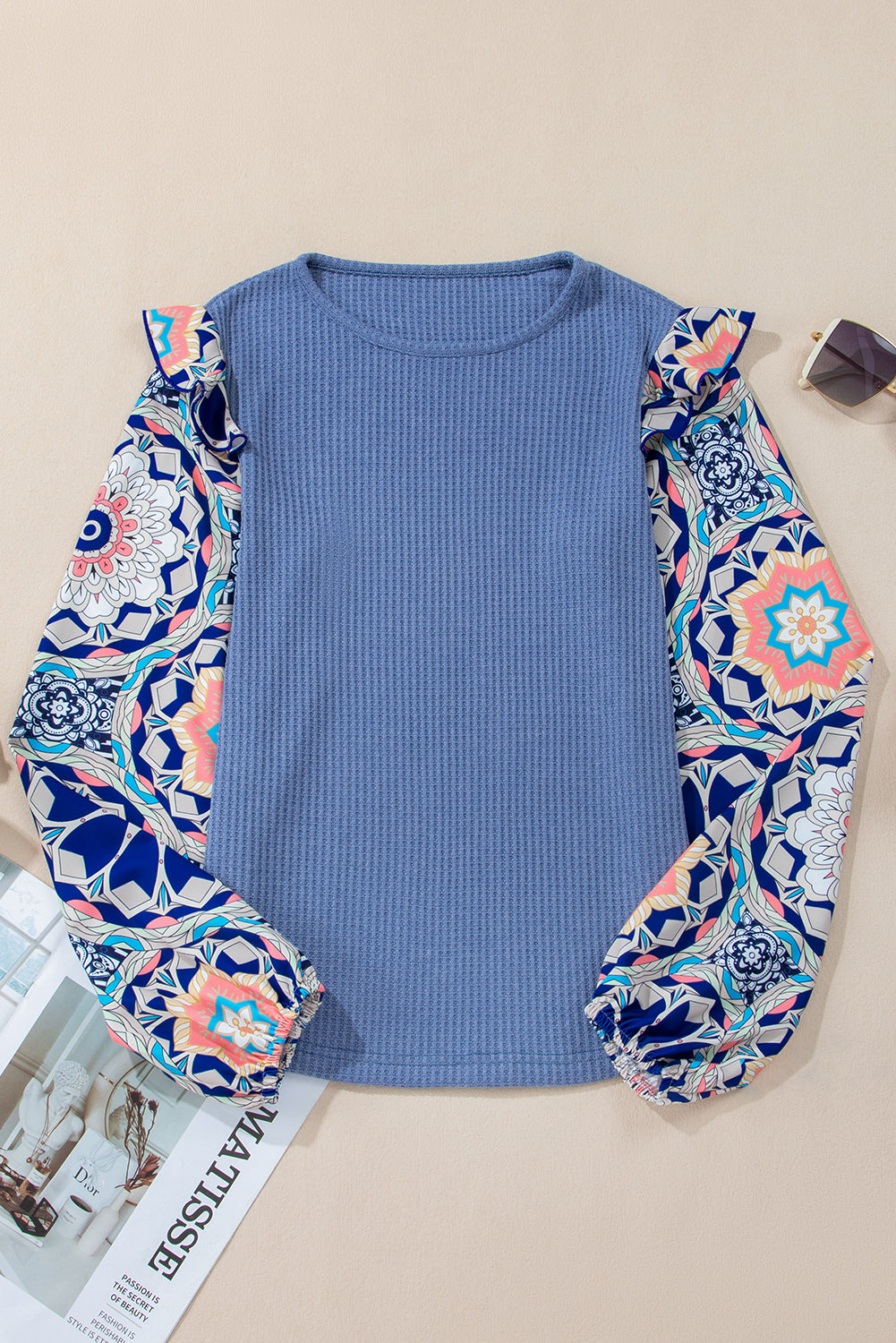 Blue top with patterned sleeves on a beige surface