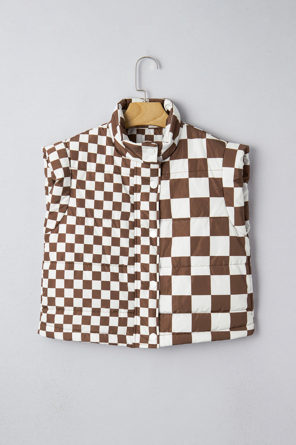 Checkered vest with brown and white pattern on a hanger against a gray background