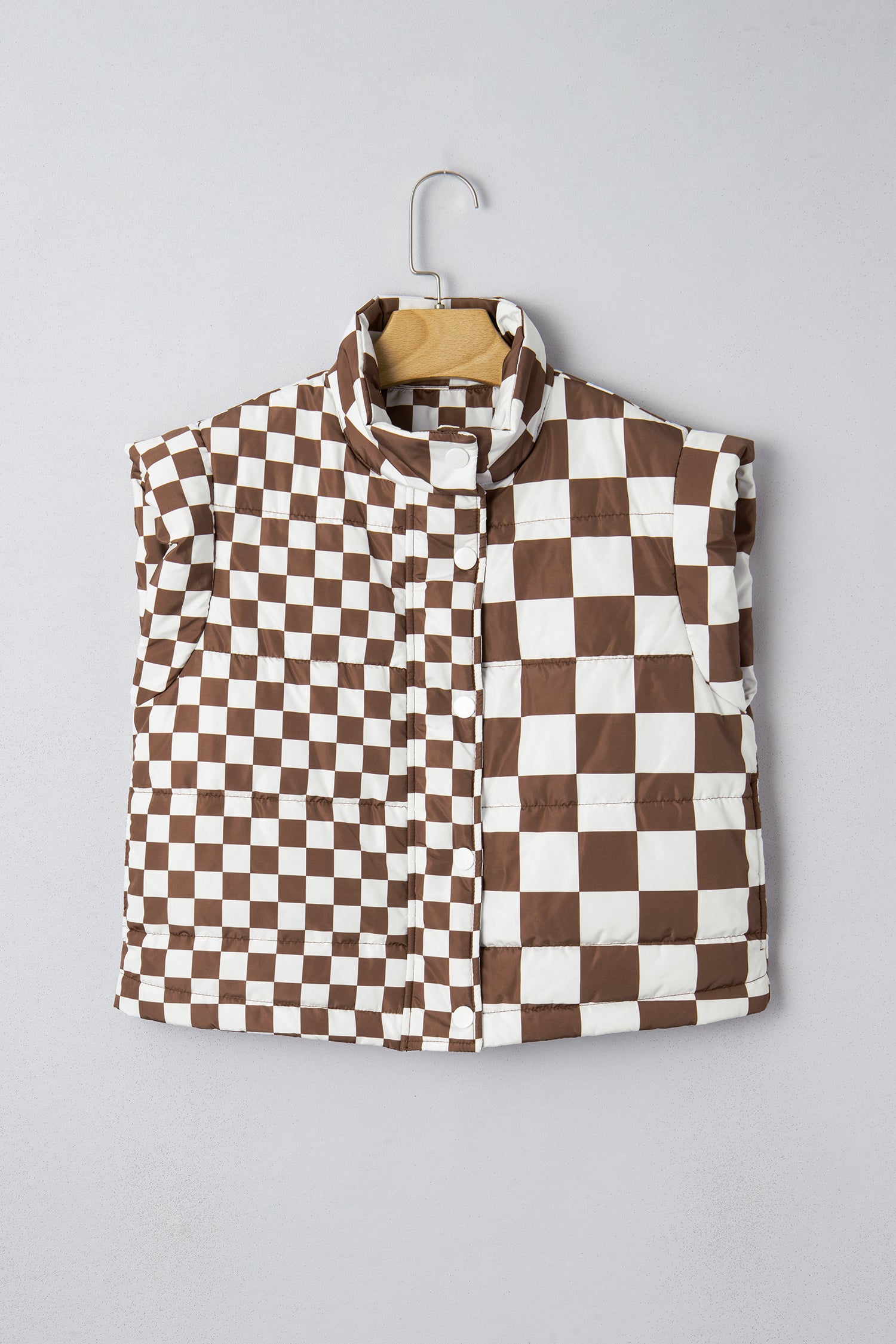 Checkered vest with brown and white pattern on a hanger against a gray background