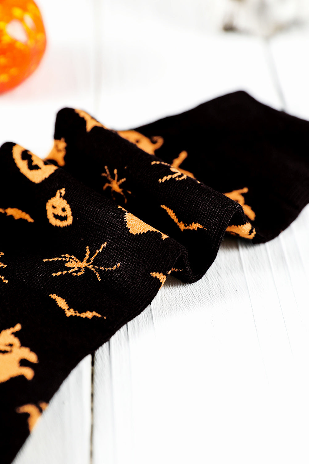 Black socks with orange Halloween patterns on a white surface.