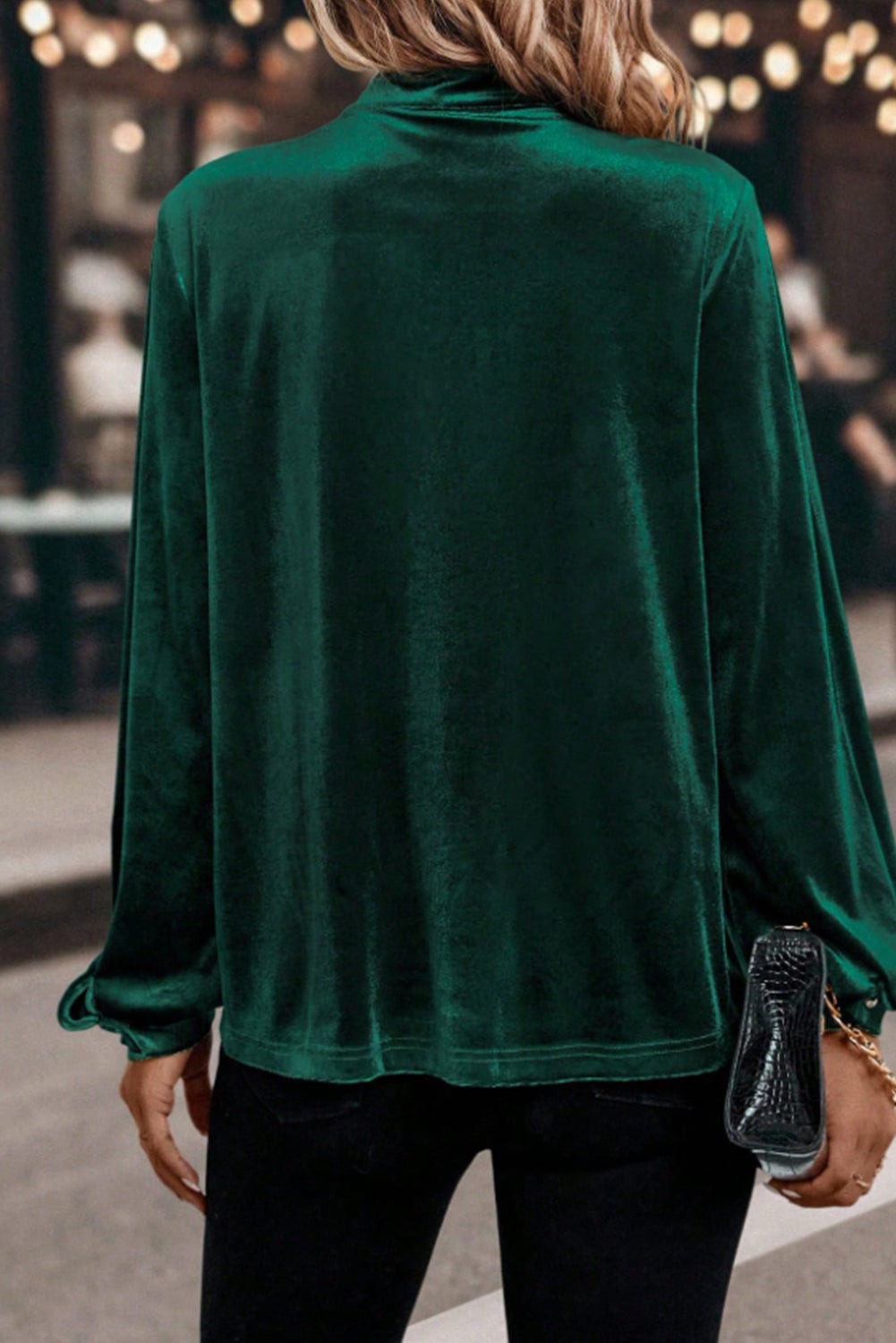 Person wearing a green velvet top with blurred background