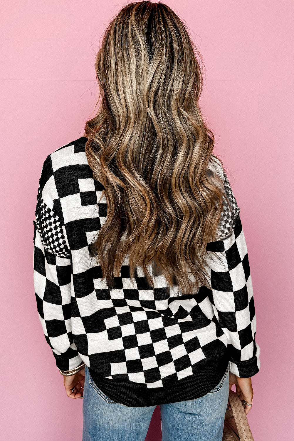 Person wearing a black and white checkered shirt against a pink background