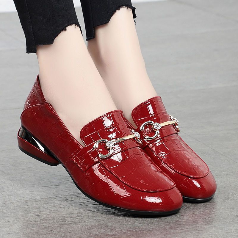 Red loafers with metallic buckles on a neutral background