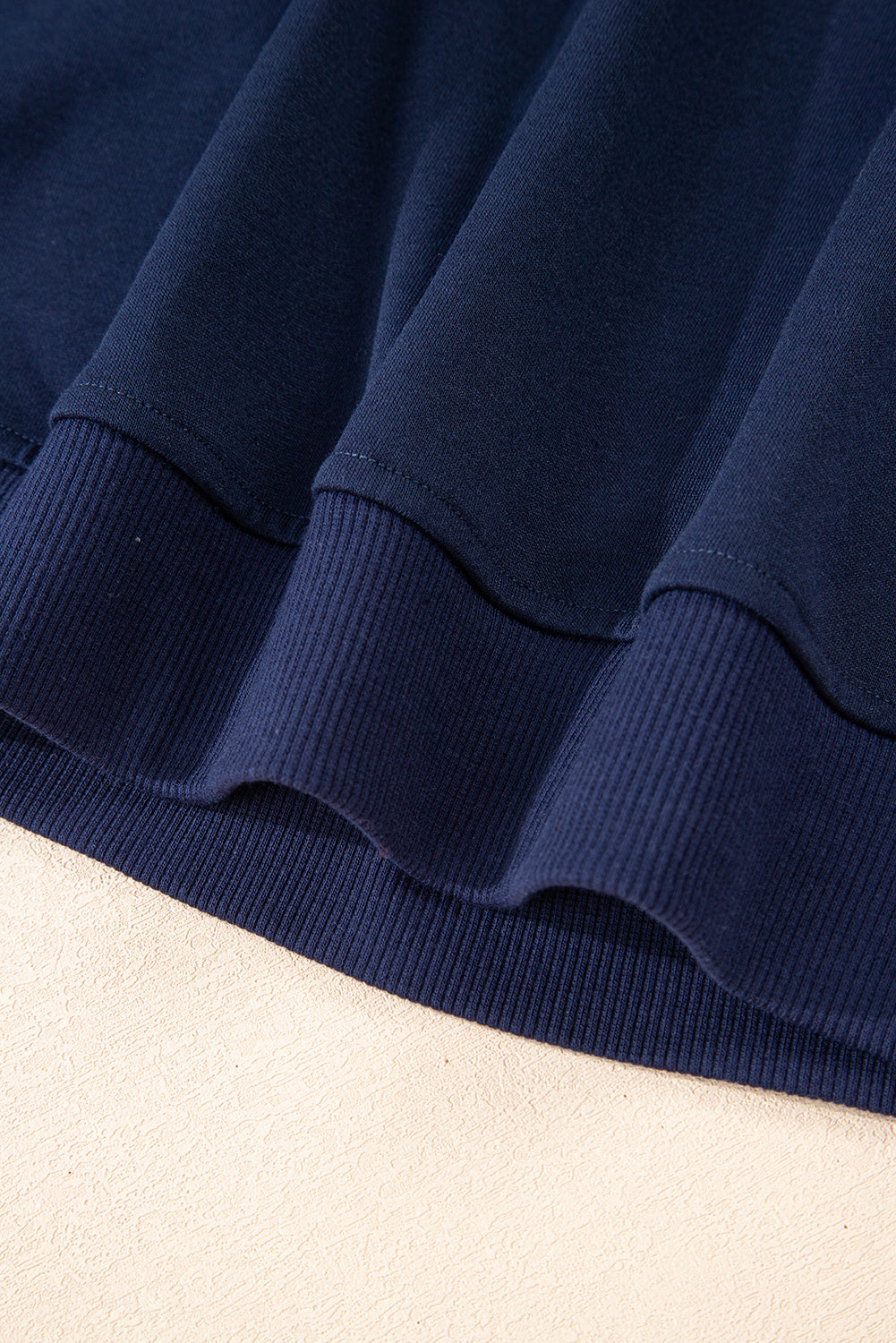 Close-up of a navy blue fabric with a textured edge on a beige background