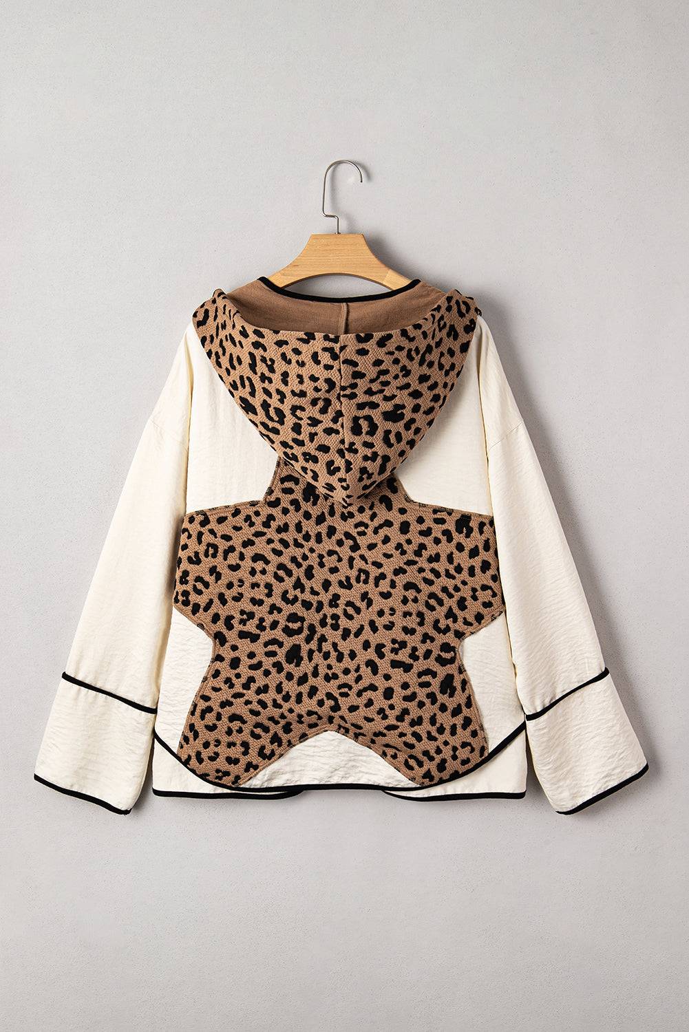 Leopard print top with white sleeves on a hanger against a gray background