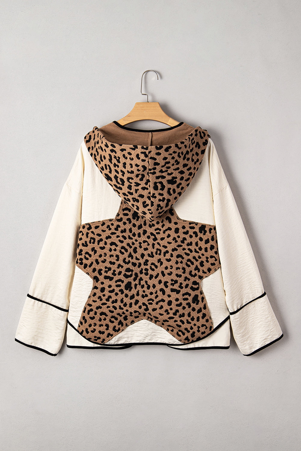 Leopard print top with white sleeves on a hanger against a gray background