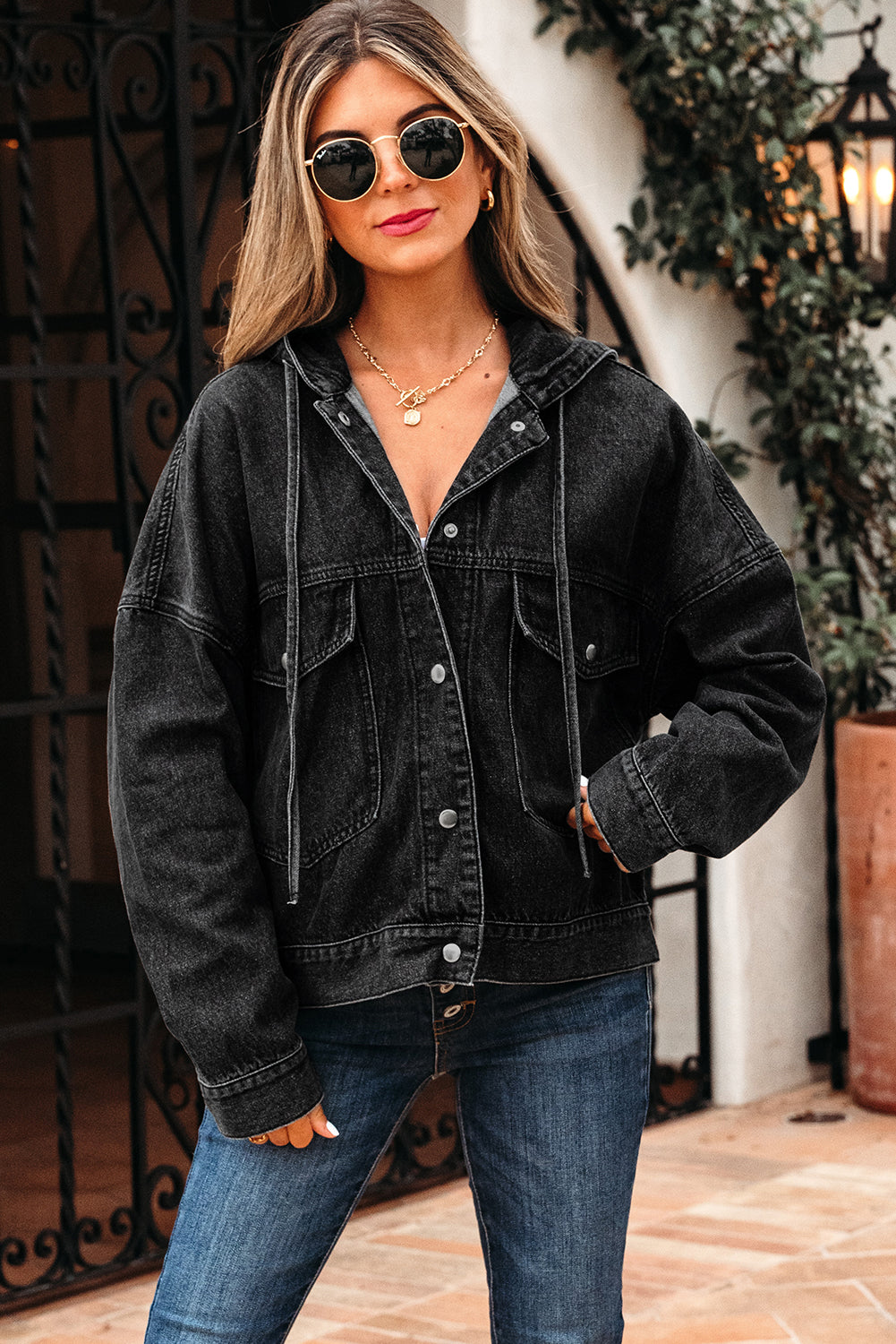 Woman wearing a black denim jacket and sunglasses outdoors.