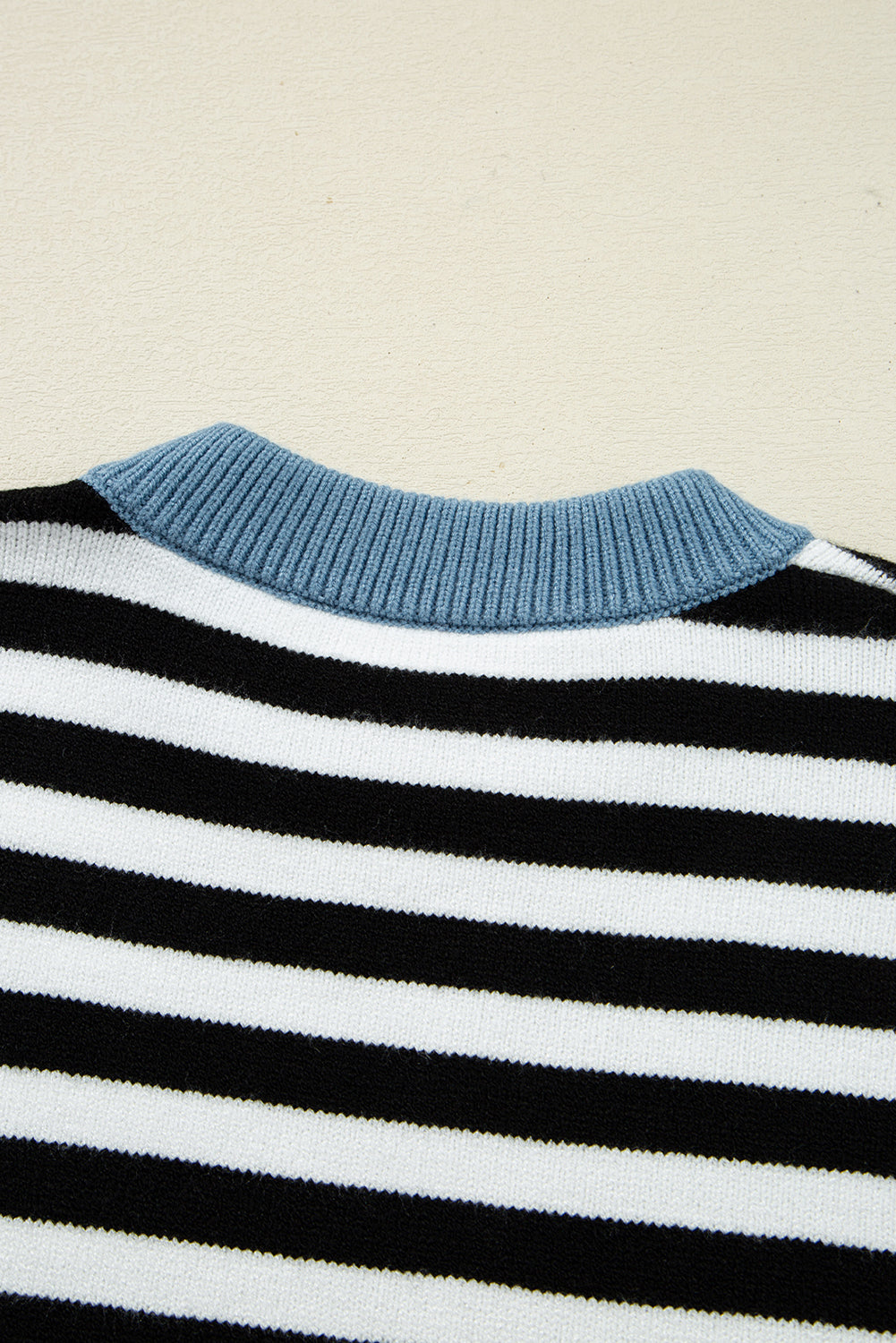 Close-up of a striped sweater with blue collar on a beige background
