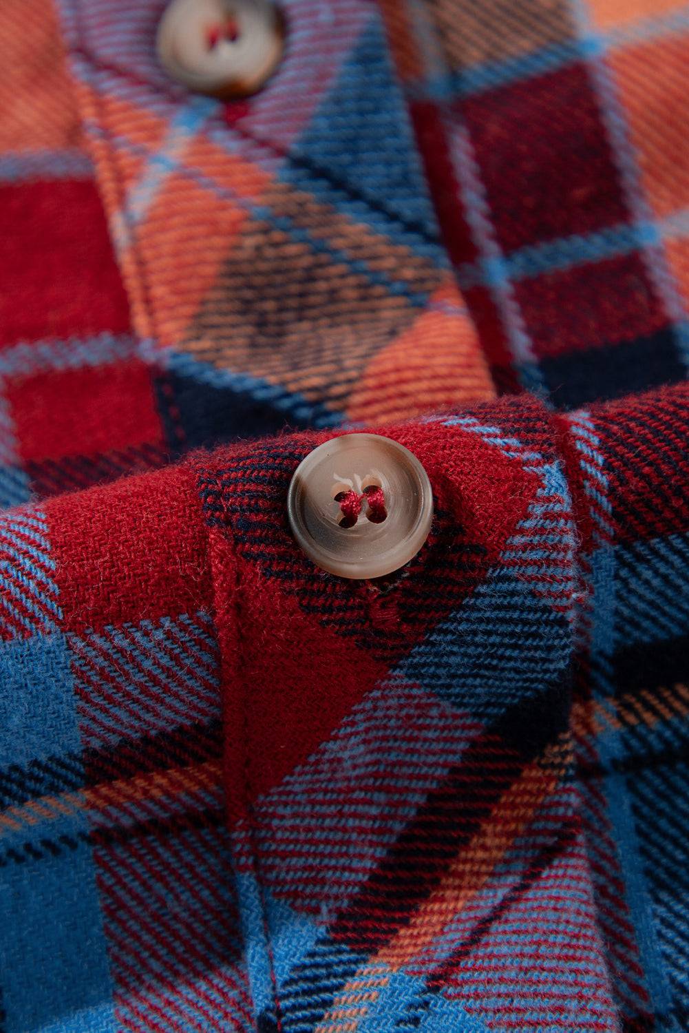 Close-up of a plaid fabric with a button on a red, blue, and orange checkered pattern.