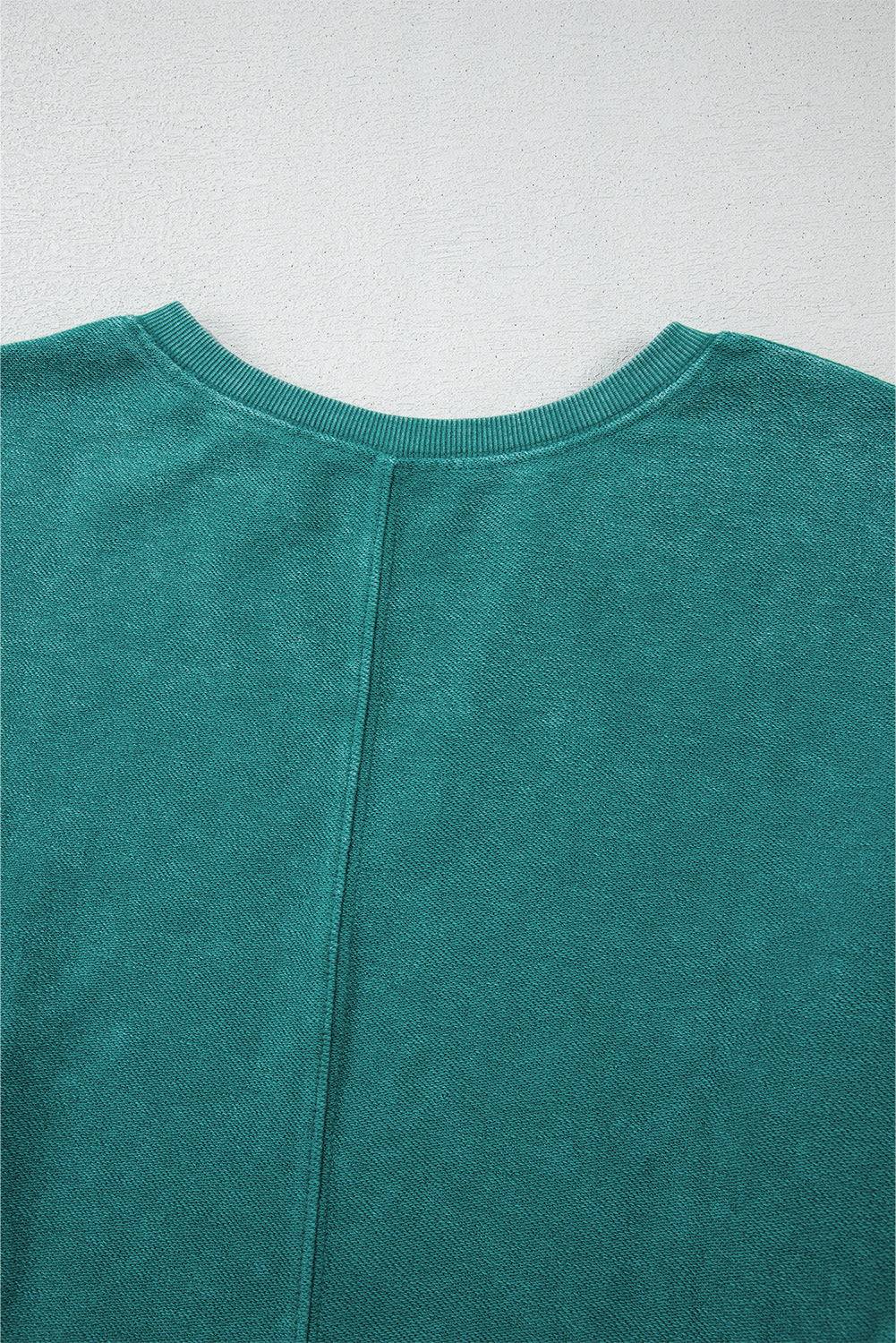 Close-up of a teal sweater on a light gray background