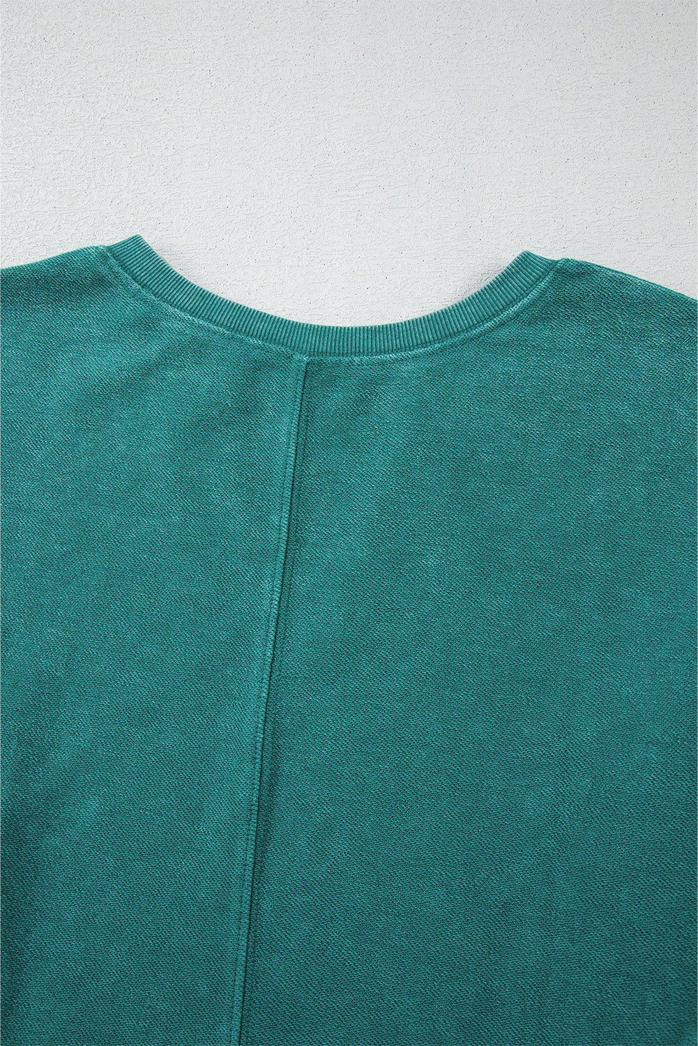 Close-up of a teal sweater on a light gray background