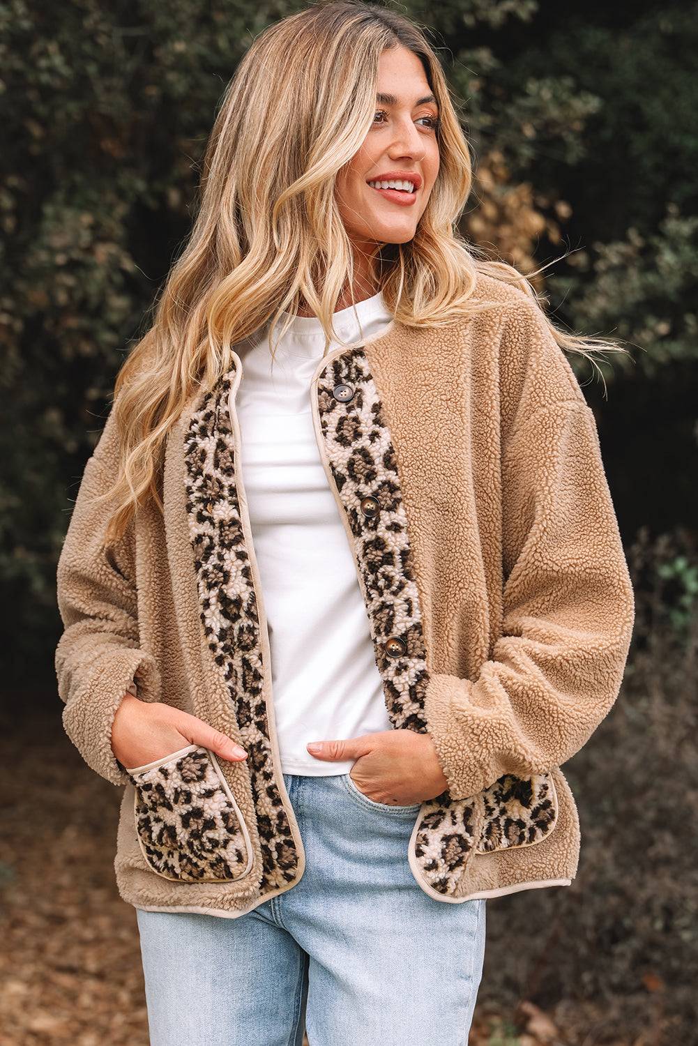Woman wearing a beige fleece jacket with leopard print accents outdoors.