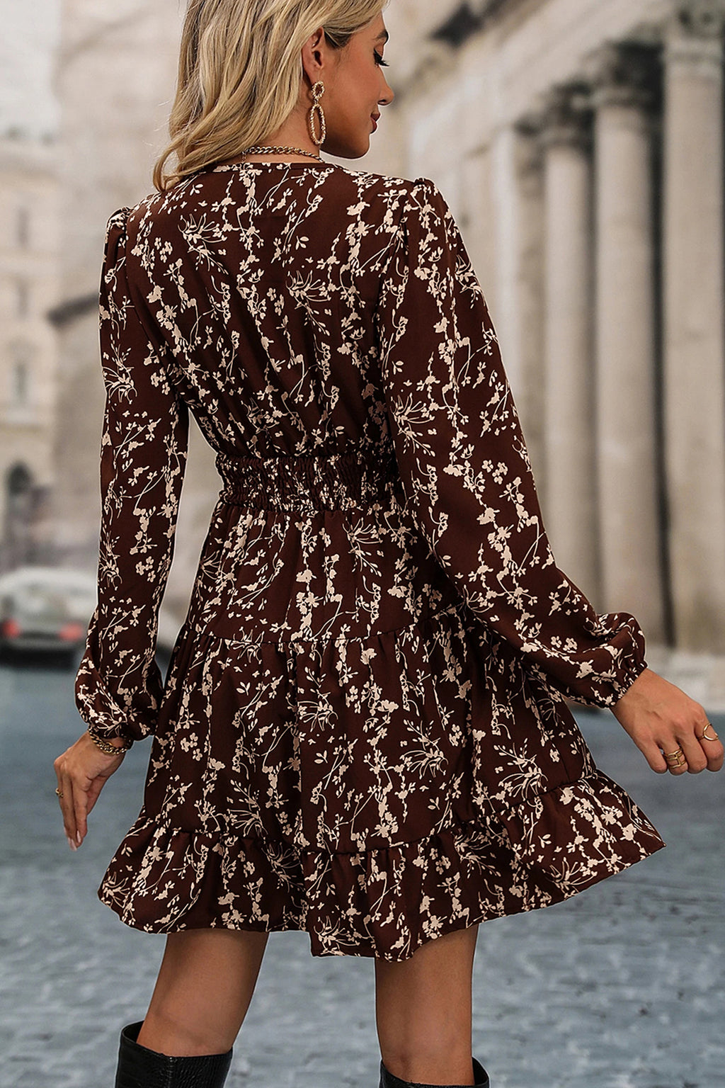 Woman wearing a brown floral dress walking on a street.
