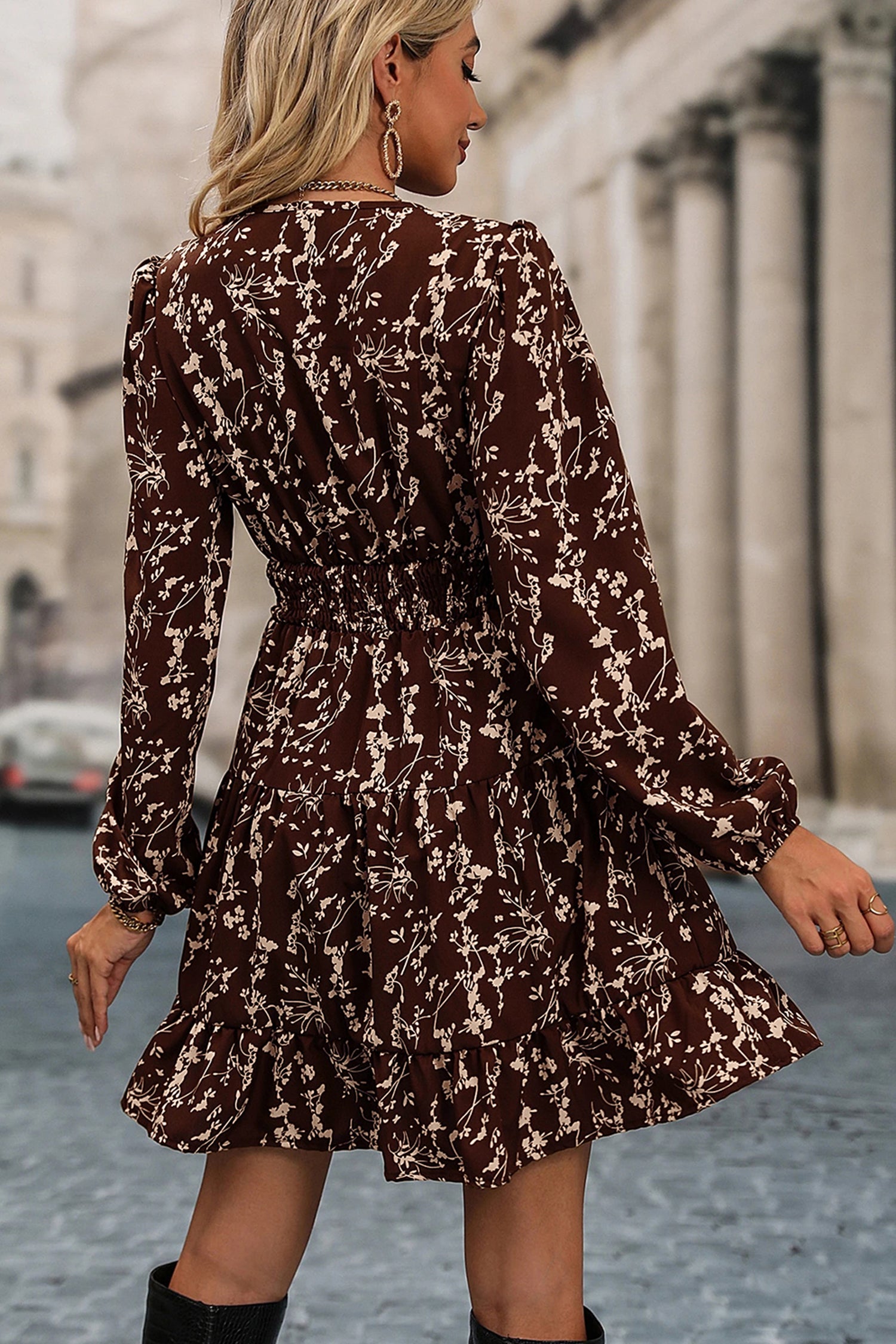 Woman wearing a brown floral dress walking on a street.