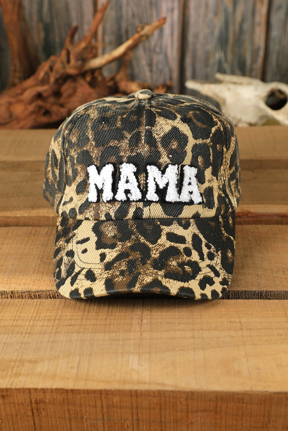 Leopard print cap with 'MAMA' text on a wooden surface
